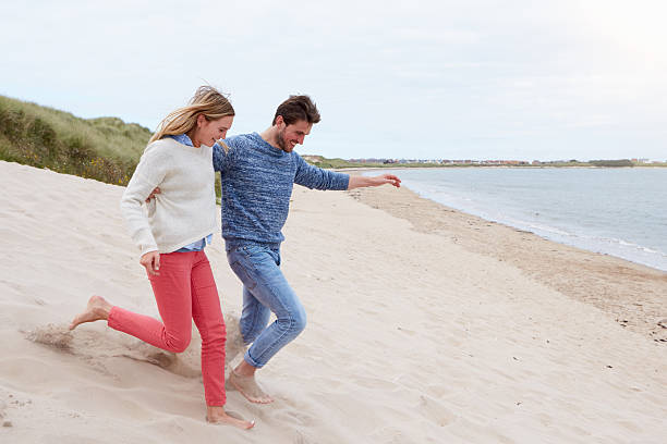 istock Couple Running Through Sand Dunes Together 510079360