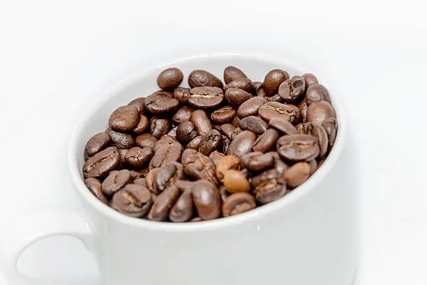 Photo of Coffee beans seed in white cup isolated highkey