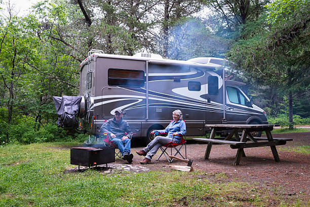 Couple relaxing near campfire Couple relaxing near campfire. Road trip in motor home. North America. rv stock pictures, royalty-free photos & images