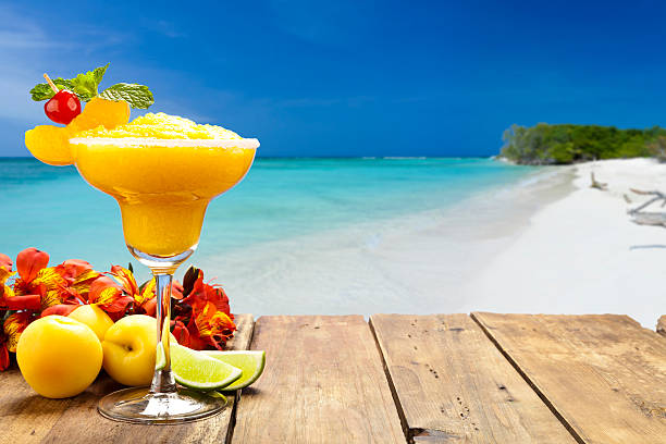 Peach daiquiri on wood table against tropical beach background Peach daiquiri on wood table against tropical beach background. The glass is placed at the left of the frame leaving a useful copy space at the center-right daiquiri stock pictures, royalty-free photos & images