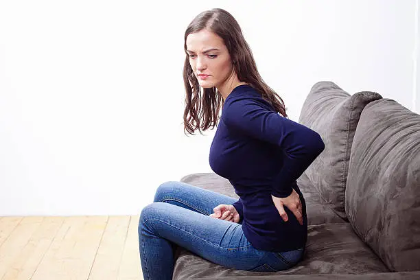 Photo of Young Woman Sitting On Sofa Suffering From Ache