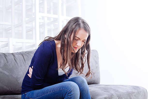 istock Young Woman Sitting On Sofa Suffering From stomach ache 510085898