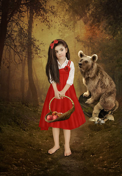 Little girl with long hair, with a basket of apples in red sundress in a forest and the bear.