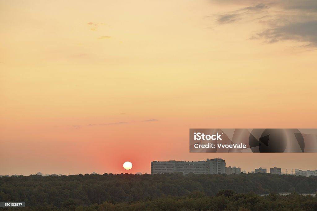 low red sun above horizon during sunrise over city low red sun above horizon during sunrise over city in summer morning Apartment Stock Photo