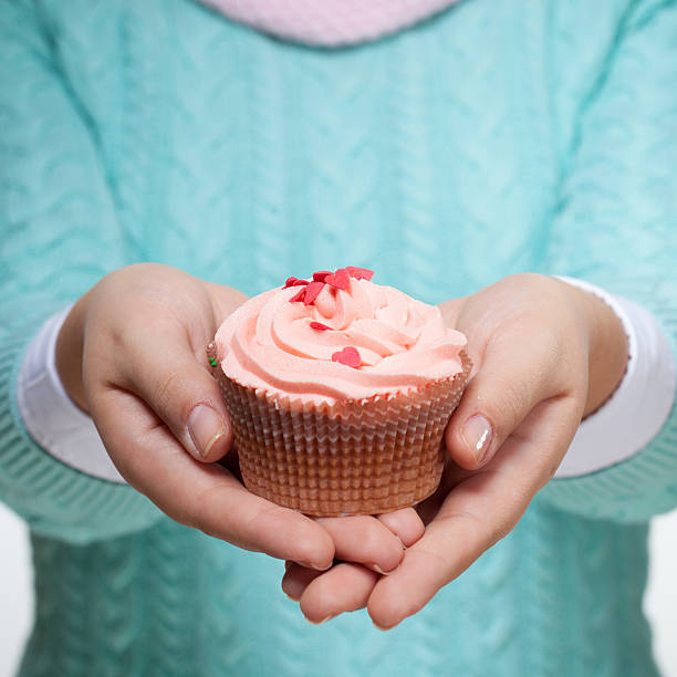 istock Woman holding a pink cupcake on white 510147936