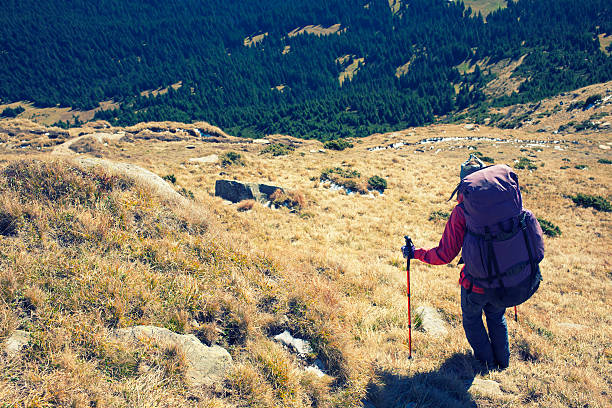 The woman with the backpack is on a dangerous slope.