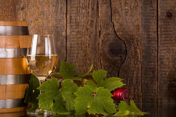 Glass of wine with bottle covered with grapeleaves