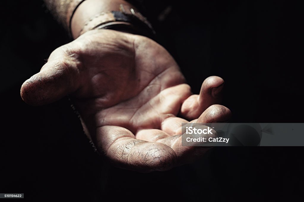 Hand emerging from the dark Hand emerging from the dark. Wrist and the gentle open hand of a hardworking man extend from the darkness. The hand is faintly cupped and the fingers are pressed together. Background in soft focus. Reaching Stock Photo