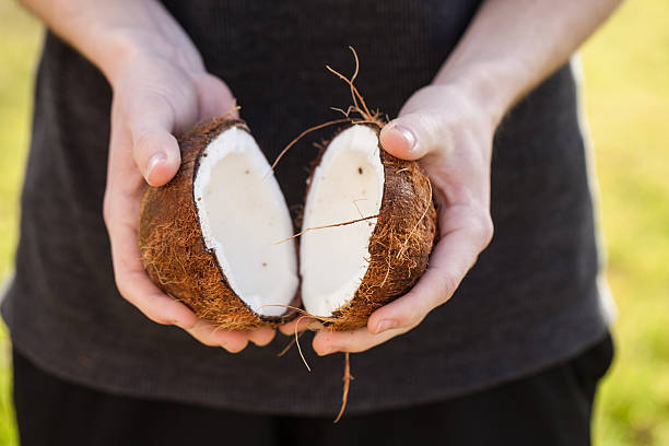 istock Two halves of open raw coconut being held by hands 510158240