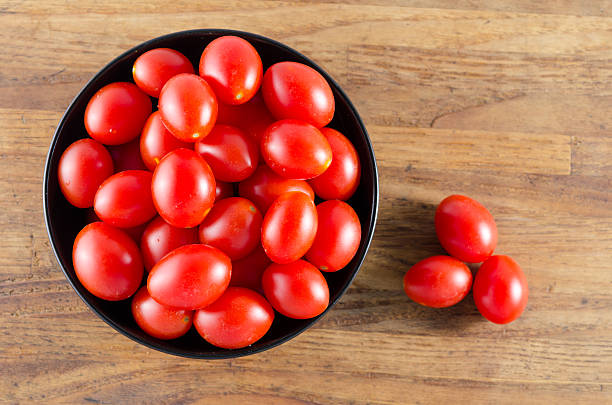 istock cherry tomatoes in a black bowl on aged wooden table 510159199