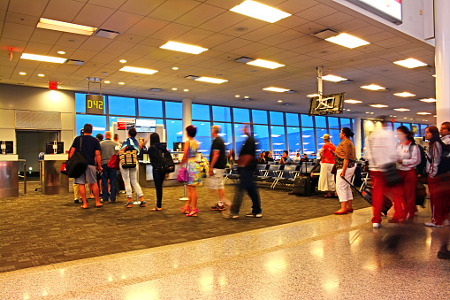 Toronto, Canada - August 7, 2014 : Passengers queuing for departure at Toronto Pearson International Airport, Terminal C. Other passengers in the background are sitting and waiting for boarding.