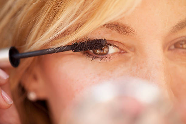 Cute  woman putting some mascara on