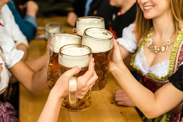 Bavarian girls in traditional Dirndl dresses are drinking beer and having fun at the Beer Fest