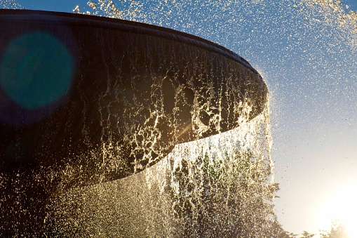 Water splashing from a city fountain, lit by the setting sun.