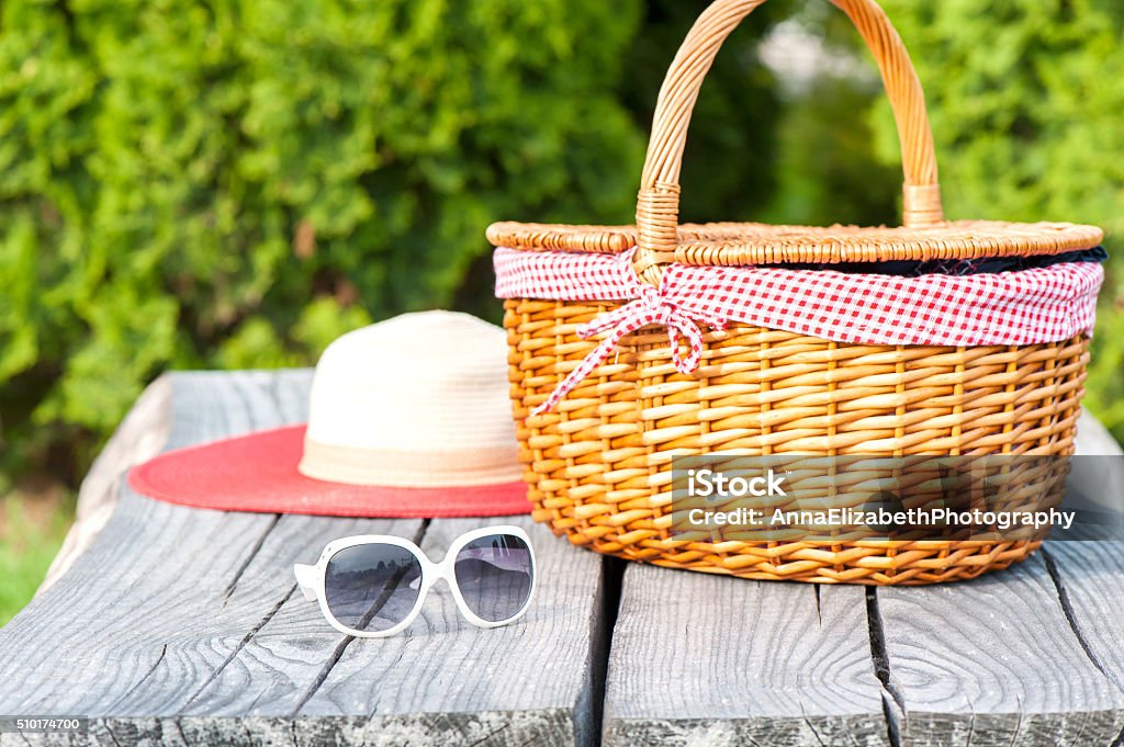 Ready for summer holidays. Sunglasses hat and wicker basket. Ready for summer holidays. White sunglasses summer hat and wicker basket on wooden table background. Multicolored vibrant outdoors horizontal image. Basket Stock Photo