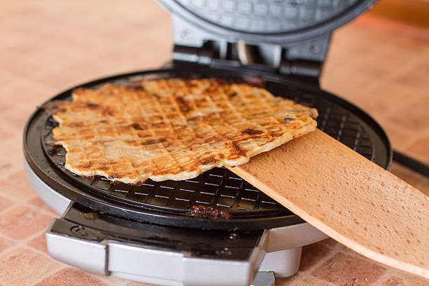 istock Homemade waffles in a waffle iron with wood spatula. 510176854