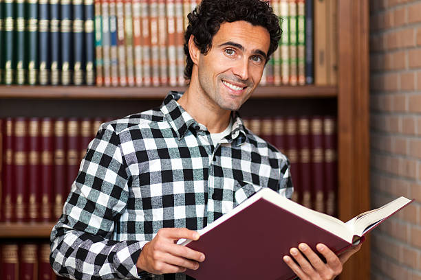 istock Handsome man stands by bookshelves 510177094