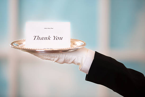 butler posiada "dziękuję" notecard na srebrna taca.  okno tle. - waiter butler luxury silver platter zdjęcia i obrazy z banku zdjęć