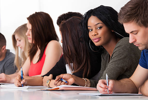 istock Confident Student Sitting With Classmates Writing At Desk 510182511