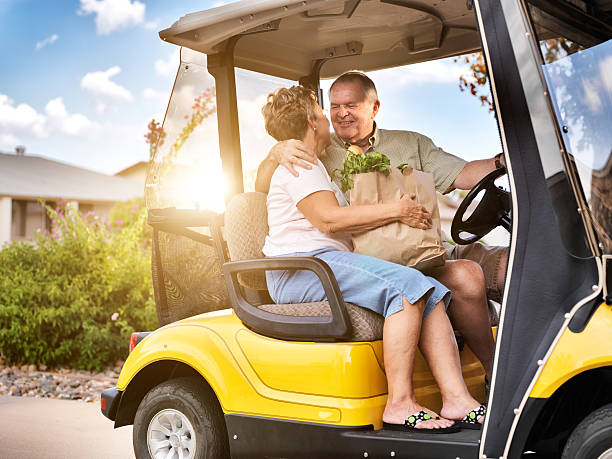 feliz casal de idosos para casa com mantimentos no carrinho de golfe - senior couple golf retirement action - fotografias e filmes do acervo