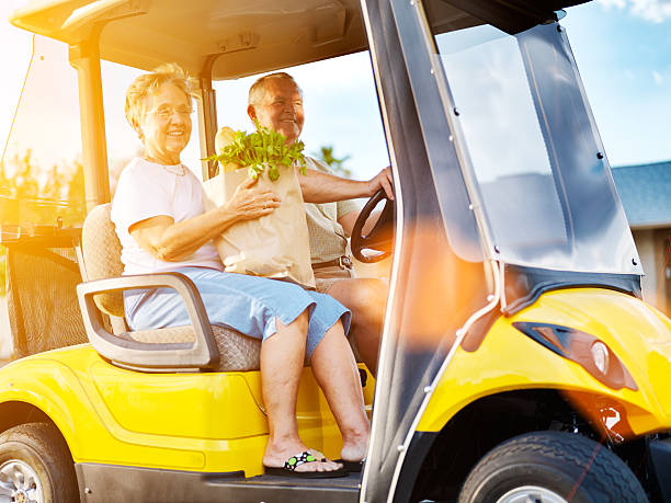 feliz casal de idosos para casa com mantimentos no carrinho de golfe - senior couple golf retirement action - fotografias e filmes do acervo