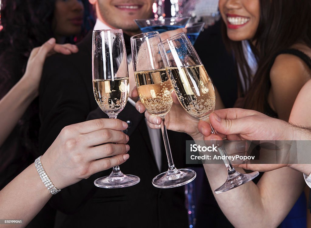 Friends Toasting Champagne At Nightclub Cropped image of friends toasting champagne flutes at nightclub Adult Stock Photo