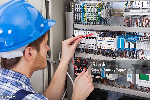 Technician Examining Fusebox With Multimeter Probe Stock Photo - Download Image Now - Electrician, Working, Electricity