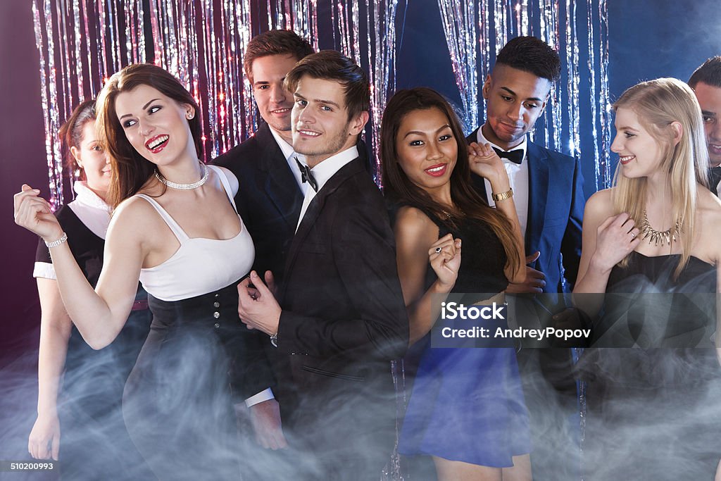 Friends Dancing At Nightclub Smiling young friends dancing together at nightclub Adult Stock Photo