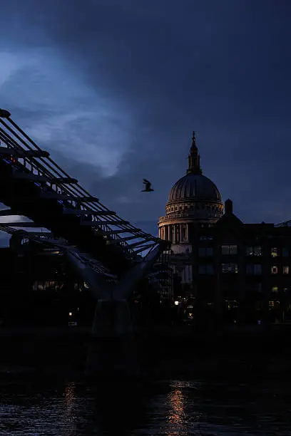 The dome of London's iconic St. Paul's Cathedral captured after sunset from a vessel aboard The River Thames with a Canon 5D Mark III.  The Millennium Bridge and a soaring seagull are seen in the foreground of the photograph.