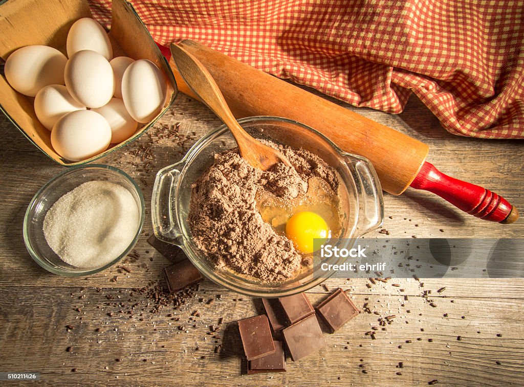 Chocolate Batter Surrounded By Fresh Ingredients Raw chocolate cake batter surrounded by eggs, sugar, chocolate and sprinkles. Shot from above with a natural rustic color and texture in horizontal orientation. Ingredient Stock Photo