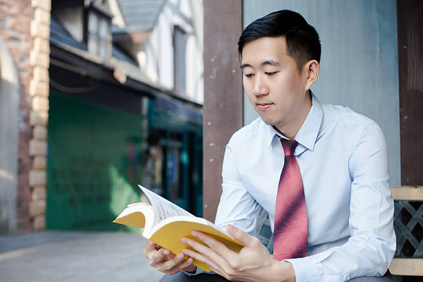 istock Asian Man Reading a Book Sitting on Bench 510218648