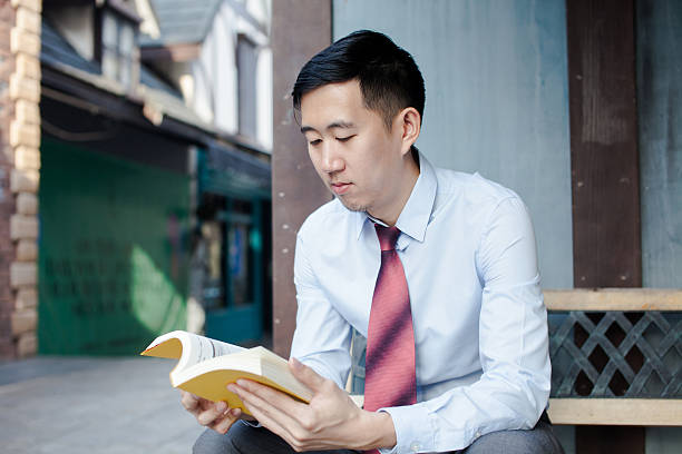 istock Asian Man Reading a Book Sitting on Bench 510218700