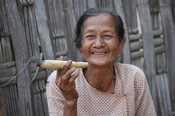 stary uśmiech azjatycki kobieta palenia na duże cygaro - handroll zdjęcia i obrazy z banku zdjęć