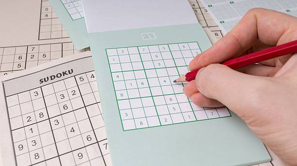 istock Sudoku puzzle and hand with pencil. 510225566