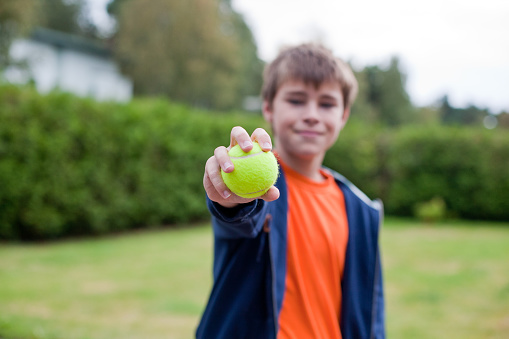little boy holding yellow tennis ball, horizontal