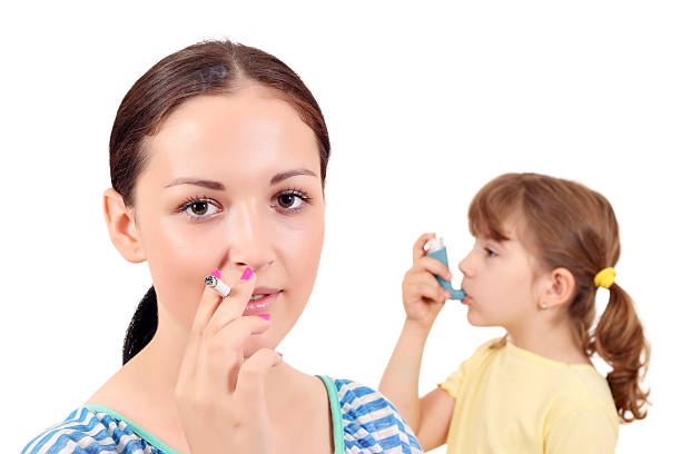 girl smoking cigarette and little girl with inhaler stock photo