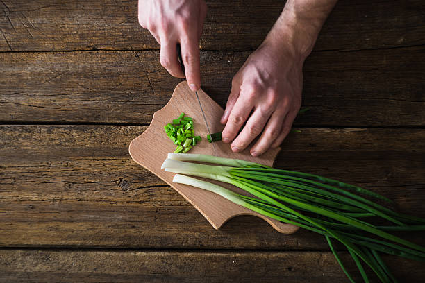 man chopped green onion on the board. Wooden table
