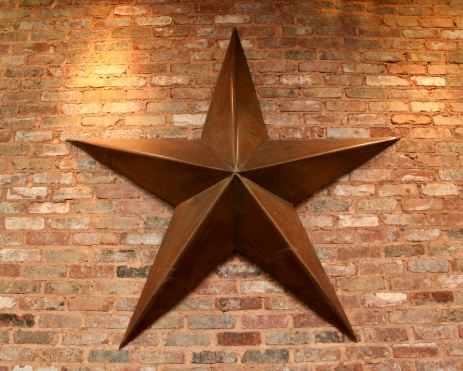 Large metal or tin star, five points, hanging on a brick wall