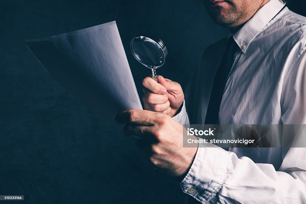 Tax inspector doing financial auditing, businessman reading cont Tax inspector doing financial auditing, businessman reading business report or contract footnotes disclaimer with magnifying glass, retro toned, selective focus Audit Stock Photo