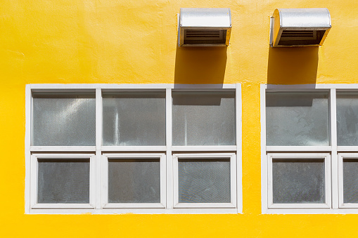 Windows and ventilation outlets on yellow business building