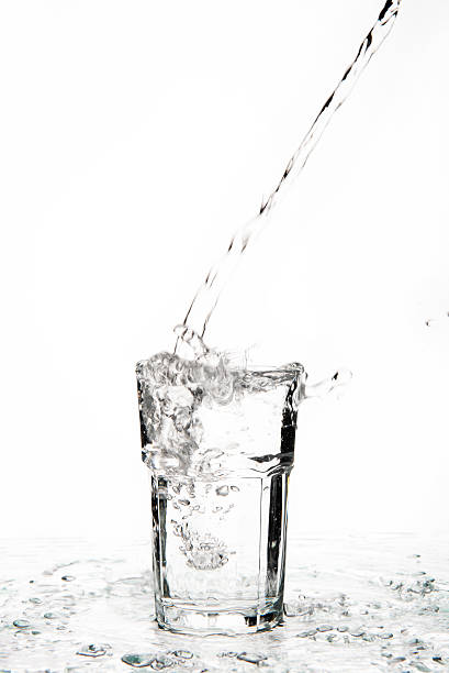 Overflowing glass of water on a glass table stock photo