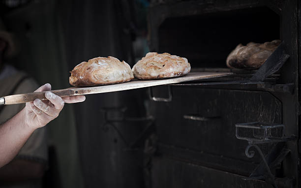 zbliżenie człowiek piekarz przedstawiamy chleb w klasycznym piec - chef baker bakery flour zdjęcia i obrazy z banku zdjęć