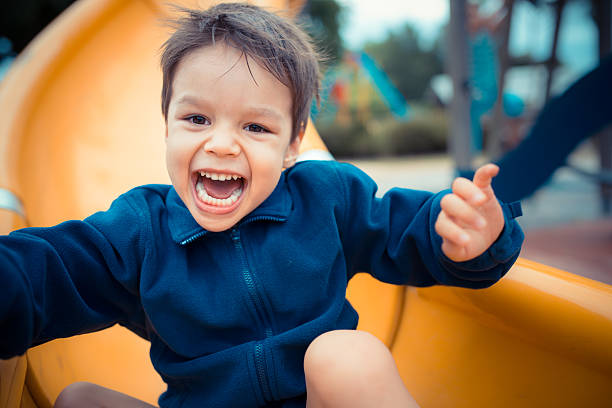 süße 3-jahre alte asiatische junge spielt auf spielplatz folie - rutschen stock-fotos und bilder