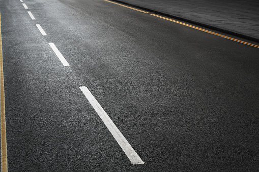 Shot of an empty road with copy space for the designer with the texture of the tarmac and white and double yellow lines.
