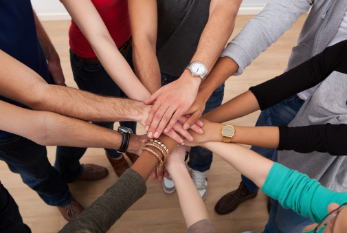 High angle view of multiethnic college students stacking hands in classroom