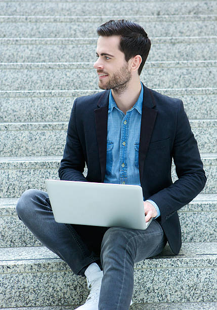 istock Young man sitting on steps with laptop 510242349