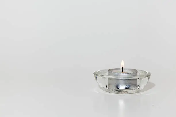 on table stay an tealight in glass on white background