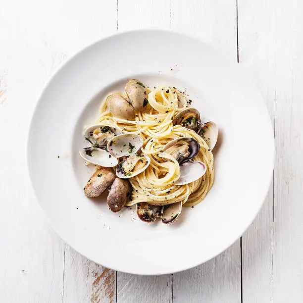 Seafood pasta with clams Spaghetti alle Vongole on white wooden background