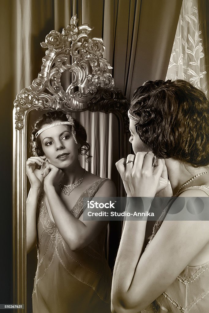 1920s lady in mirror Stunning vintage 1920s woman looking in an antique mirror Flapper Style Stock Photo