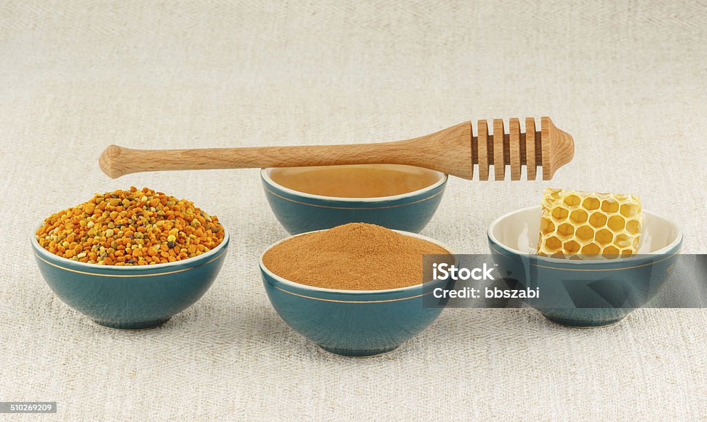 Honey, honeycomb, pollen granules and cinnamon in bowls Pollen granules, honeycomb, honey and cinnamon in green porcelain bowls with wooden dipper, on rustic table cloth Antioxidant Stock Photo